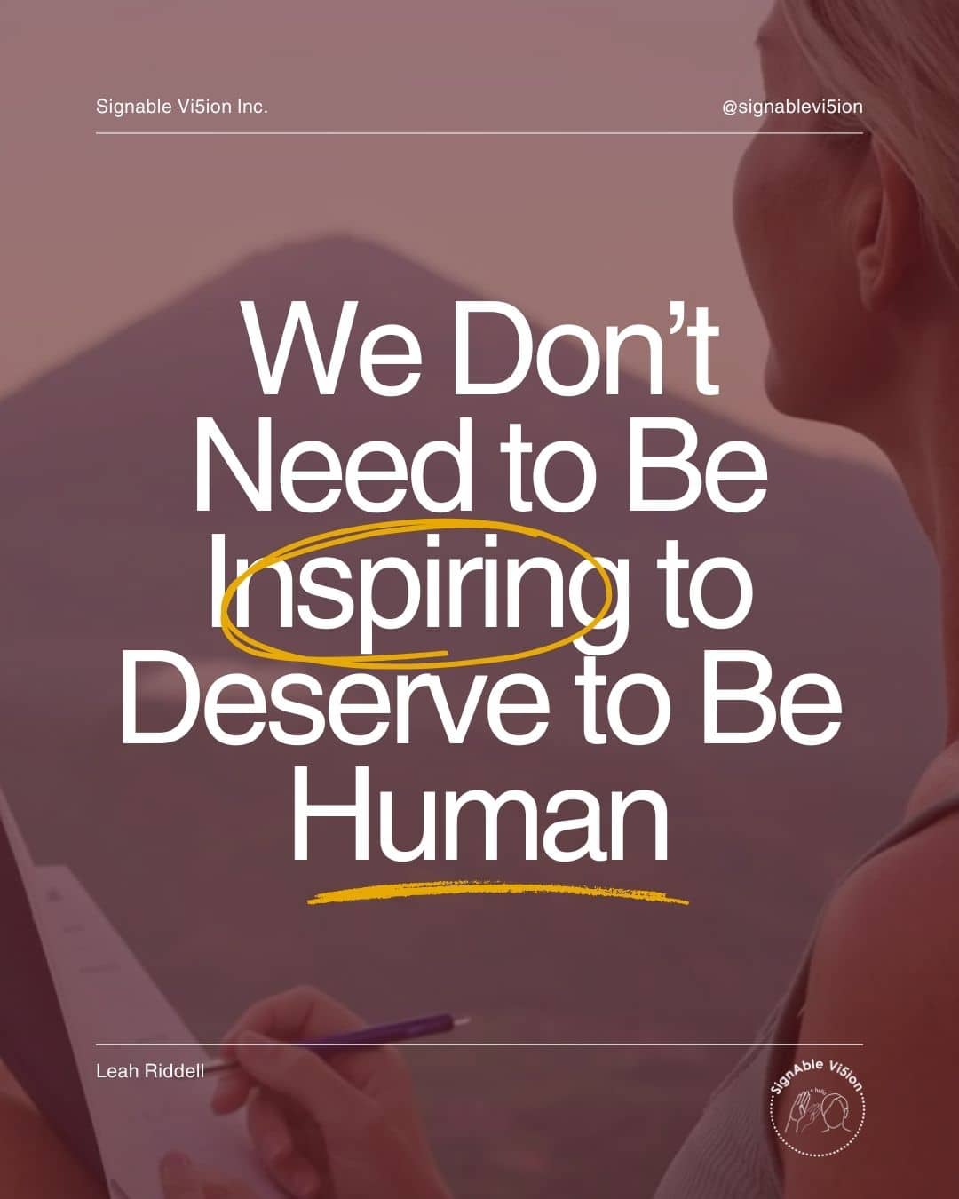 A soft, warm-toned photo of a woman seen from the side, sitting outdoors and writing in a notebook with mountains in the background. Over the image is large white text that reads, “We Don’t Need to Be Inspiring to Deserve to Be Human,” with the word “Inspiring” circled and underlined in yellow. At the top is the name “Signable Vi5ion Inc.” and the handle @signablevision. At the bottom left is Leah Riddell’s name, and at the bottom right is the SignAble Vi5ion logo.